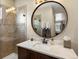 Modern bathroom with a glass shower, marble countertop, and a decorative round mirror at 12431 Red Fox Way, Broomfield, CO 80021