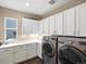 Bright laundry room with modern washer, dryer, white cabinets and countertop at 12431 Red Fox Way, Broomfield, CO 80021