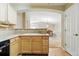 Open kitchen view showcasing wood cabinets, tile backsplash and countertops, and views to the dining room at 9816 W Freiburg Dr # A, Littleton, CO 80127