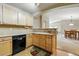 Open kitchen view showcasing stainless steel dishwasher, wood cabinets, countertops, and a view to the dining room at 9816 W Freiburg Dr # A, Littleton, CO 80127