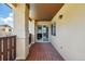 View of the covered porch with brown wood flooring and railings, along with tan columns and view to the property at 9816 W Freiburg Dr # A, Littleton, CO 80127