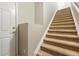 Carpeted staircase, with a door to the side, leads upstairs inside the home at 9816 W Freiburg Dr # A, Littleton, CO 80127