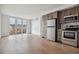Bright, open-concept living room with modern kitchen featuring stainless steel appliances and wood cabinets at 3575 Chestnut Pl # 702, Denver, CO 80216