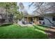 Spacious backyard with an outdoor deck, trampoline, seating area, and well-maintained lawn at 1423 S Eudora St, Denver, CO 80222