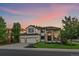 Stunning two-story home with a three-car garage, manicured lawn, and brick accents at sunset at 10701 Flagler Dr, Parker, CO 80134