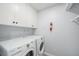 Clean laundry room with white cabinets and modern washer and dryer units at 2203 S Holly St # 3, Denver, CO 80222