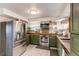 Modern kitchen featuring green cabinetry, stainless steel appliances, open shelving, and updated countertops at 1149 S Kittredge St, Aurora, CO 80017