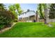 Lush green backyard featuring a brick home exterior, patio area, and mature landscaping, perfect for relaxation at 9765 W 77Th Dr, Arvada, CO 80005