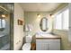 Bathroom featuring tiled shower with glass doors, vanity, and a window providing natural light at 9765 W 77Th Dr, Arvada, CO 80005
