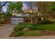 Charming home featuring a well-manicured lawn, mature trees, and a spacious driveway with blue garage doors at 9765 W 77Th Dr, Arvada, CO 80005