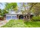 Inviting two-story home boasting a spacious driveway, blue garage doors, and well-manicured front yard at 9765 W 77Th Dr, Arvada, CO 80005
