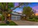 Beautiful home exterior with a lush front lawn, mature trees, and a welcoming entrance at twilight at 9765 W 77Th Dr, Arvada, CO 80005