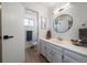 Bright bathroom with white cabinets, round mirror, and an adjacent toilet room at 10092 Lee St, Broomfield, CO 80021