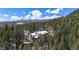 Aerial view of the house nestled among a dense evergreen forest and mountain backdrop at 846 Circle K Ranch Rd, Evergreen, CO 80439