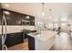 Open kitchen with dark cabinets, stainless appliances, large island, and wood floors at 12770 Tamarac St, Thornton, CO 80602