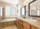 Bathroom with double vanity and sinks, tiled floors, and soaking tub at 11060 River Oaks Ln, Commerce City, CO 80640