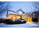 Charming home exterior at twilight with a covered porch and snow-covered landscaping at 11060 River Oaks Ln, Commerce City, CO 80640
