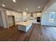 Bright and airy kitchen features white cabinets, stainless appliances, large island, and wood floors at 1131 Joseph Pl, Erie, CO 80026