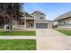 Charming two-story home with brick accents, gray garage door, well-kept lawn, and a welcoming front porch at 15378 E 99Th Way, Commerce City, CO 80022