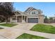 Charming two-story home with brick accents, a gray garage door, well-kept lawn, and a welcoming front porch at 15378 E 99Th Way, Commerce City, CO 80022