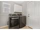 This laundry room features a gray washer and dryer, white cabinets and neutral paint at 15378 E 99Th Way, Commerce City, CO 80022