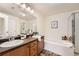 Bathroom featuring double sinks, a soaking tub, and a separate glass shower at 10056 W Unser Dr # 204, Littleton, CO 80127