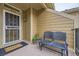 Charming front porch with a cozy bench, 'welcome' doormat, and decorative floral wreath on the front door at 10056 W Unser Dr # 204, Littleton, CO 80127