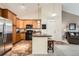 Well-lit kitchen with wood cabinets, stainless steel refrigerator, and an island with seating at 10056 W Unser Dr # 204, Littleton, CO 80127