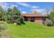 Charming brick home featuring a well-manicured lawn and mature tree providing shade and curb appeal at 6155 Meadowbrook Dr, Morrison, CO 80465