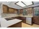 Bright kitchen with white countertops, cooktop, stainless steel dishwasher, and wood cabinetry at 6155 Meadowbrook Dr, Morrison, CO 80465