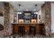 Elegant bar area featuring stone accents, wooden bar, display cabinets and pendant lighting at 6371 Diamond Ridge Pkwy, Castle Rock, CO 80108