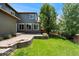 Fenced backyard with a manicured lawn, brick patio, and mature trees at 10550 Sedalia St, Commerce City, CO 80022