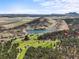 Breathtaking aerial view of a golf course, a serene lake, and rolling hills under a clear sky at 6584 Pike Cir, Larkspur, CO 80118