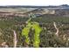 Scenic aerial view featuring a golf course with a lake and lush surrounding forest, in a serene landscape at 6584 Pike Cir, Larkspur, CO 80118