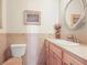 Cozy powder room featuring a tiled wall, vanity with storage, and a decorative mirror with floral accents at 6584 Pike Cir, Larkspur, CO 80118
