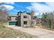 Charming home with a green garage door, well-kept lawn, and a lovely deck, surrounded by lush trees at 6584 Pike Cir, Larkspur, CO 80118
