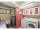 Functional laundry room with updated appliances, practical utility sink, and ample storage in overhead cabinets at 6584 Pike Cir, Larkspur, CO 80118