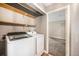 Laundry room includes full-size, modern washer and dryer with shelving for storage at 381 S Ames St # F204, Lakewood, CO 80226