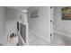 Upstairs hallway leading to bedrooms, featuring neutral tones, a wrought iron railing, and modern décor at 8307 S Garland Cir, Littleton, CO 80128