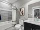 Modern bathroom with gray tiled walls, a bathtub with shower, and a vanity with black cabinets at 5716 Boston Ct, Denver, CO 80238