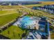 Aerial view of a neighborhood pool with a slide, tables with umbrellas, lush lawns and a community of homes at 5716 Boston Ct, Denver, CO 80238