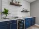 Wet bar featuring blue cabinets, marble countertop, mini fridge and decor at 5716 Boston Ct, Denver, CO 80238