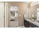 Bathroom featuring dual sinks with granite countertops, a shower, and a view into the Primary bedroom at 12835 Randles Ave, Parker, CO 80134