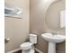Stylish powder room featuring a modern pedestal sink, round mirror, and beach-themed art at 12835 Randles Ave, Parker, CO 80134