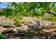 Backyard water feature cascading over rocks and logs, surrounded by lush greenery and landscaping at 9688 Chesapeake St, Highlands Ranch, CO 80126