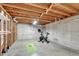 Unfinished basement with exposed wood ceiling, cement walls, and workout equipment at 4040 S Inca St, Englewood, CO 80110