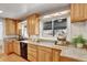 Well-lit kitchen featuring granite countertops, wooden cabinets, and updated appliances at 4040 S Inca St, Englewood, CO 80110