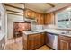 Kitchen with wood cabinets, stainless dishwasher, and island opens to breakfast nook with brick accent wall at 3225 S Race St, Englewood, CO 80113