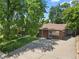 Inviting brick home with a tidy lawn and concrete driveway leading to a rear garage, shaded by mature trees at 1373 S Cape Way, Lakewood, CO 80232