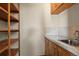 Functional utility room with shelving, countertop, stainless steel sink, and wooden cabinets for storage needs at 1373 S Cape Way, Lakewood, CO 80232
